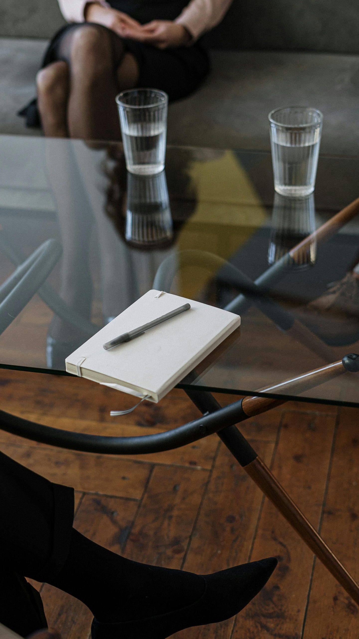 Close-up of a counseling session with two glasses of water and a notepad on a glass table.